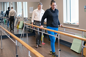 A female amputee patient walks in a rehabilitation gym.